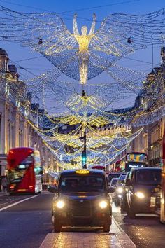 cars driving down a street with christmas lights on the sides and angel decorations above them