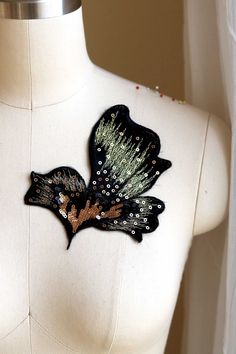 a white mannequin with a black and brown butterfly on it's chest