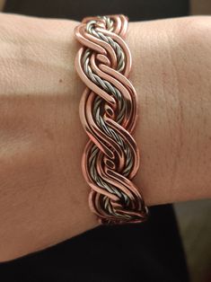 a woman's hand with a bracelet on it, that is made out of copper and silver wire