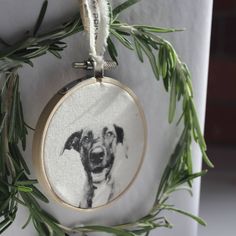 an embroidered ornament with a dog's face hanging on a tree branch