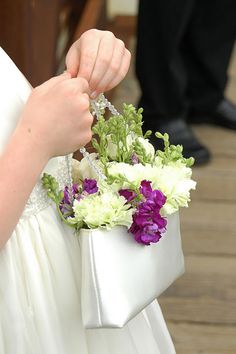 a woman in a white dress holding a bag with flowers