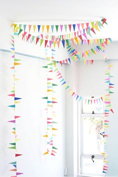 multicolored paper streamers hanging from the ceiling in a room with white walls