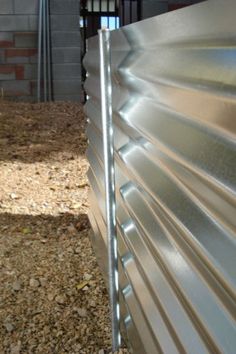 the side of a building with metal slats on it's sides and a brick wall in the background