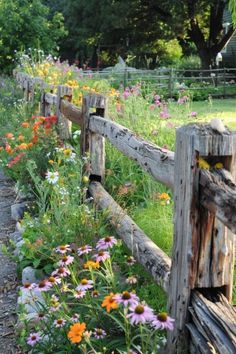 a wooden fence surrounded by flowers and grass