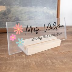 a clear acrylic sign that says, miss wilson helping little minds grow on it