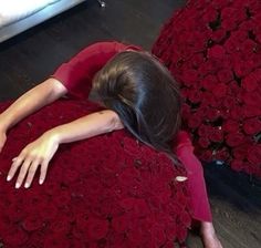 a woman laying on top of a giant red rose covered bed in a room filled with roses