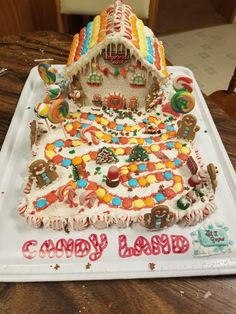 a decorated cake sitting on top of a white tray covered in frosting and candies