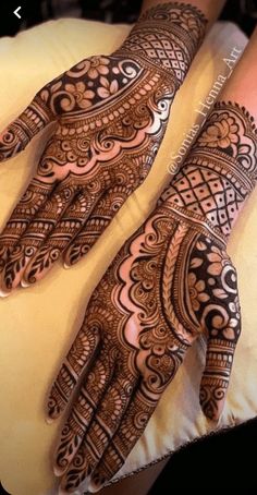 two hands with henna tattoos on them