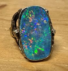 Details:This STUNNING & Absoilutely Custom Unique 1 of 1 MASSIVE 16+ carat  Black Opal 18k Yellow Gold Statement Ring is a museum quality rarity! The ring features a rainbow cascade of color in the giant black opal stone upheld by two intertwined sirens, one on each side of the band. The ring displays wear from daily use to the gold and heavy wear to the opal such as chips and heavy crazing (see photos). The cascade of colors in this opal are absolutely mesmerizing and not done justice by photo or video. The gold is not hallmarked but acid tested for 18k. This is a true 1 of 1, once in a lifetime piece. This is befitting as a true collection completion piece. It is extraordinary in every sense of the word. What you see pictured here is what you will be receiving. This listing is for the RI Black Opal Stone, Ring Displays, Custom Ring, Opal Stone, 1 Of 1, Sirens, Black Opal, A Rainbow, Custom Rings