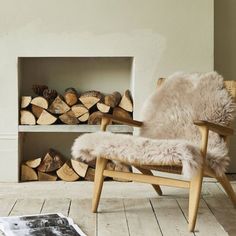 a chair sitting in front of a fire place filled with logs and a book on the floor