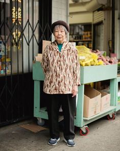 an older woman standing in front of a fruit stand