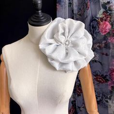 a mannequin wearing a white dress with a large flower on it's back