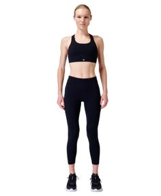 a woman in black sports bra top and leggings standing with her hands on her hips