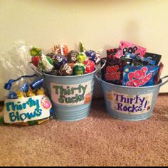 three buckets filled with candy sitting on top of a floor next to a wall