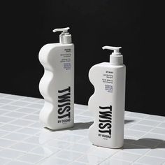 two white bottles sitting on top of a tiled counter