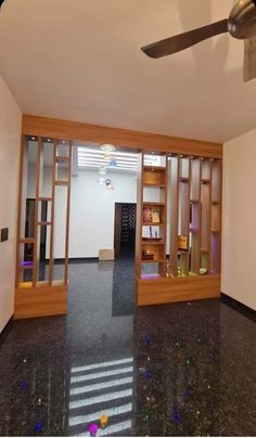 an empty room with a ceiling fan and glass doors leading to another room that has several bookshelves in it