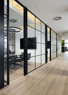 an empty conference room with glass walls and wood flooring is seen in this image