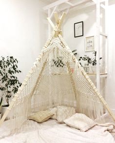 a white hammock hanging from the ceiling next to a potted plant