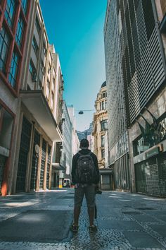 a man with a backpack is standing in the middle of an alleyway between two buildings