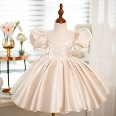 Expertly crafted with a princess silhouette and short puff sleeves, this tea length flower girl dress is perfect for any special occasion. Made from satin fabric in a beautiful champagne color, it features a back zip and bow/tie back for a chic and elegant look. Ideal for weddings, communions, and more. Dress For Kids 11-12 Wedding Champagne, Elegant Kids Dresses, Children’s Bridesmaid Dresses Champagne, Lace And Satin Dress For Kids, Champagne Bridesmaid Dresses Children, Champagne Dresses For Kids, Dresses For Eid, Flower Girl Outfits, Puff Sleeve Design