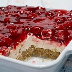 a cake in a white dish with cherries on top