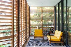 two yellow chairs sitting on top of a white floor next to wooden slatted walls