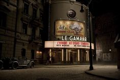 the marquee for le gamair is lit up in front of an old car