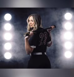 a woman holding a baseball bat in front of lights