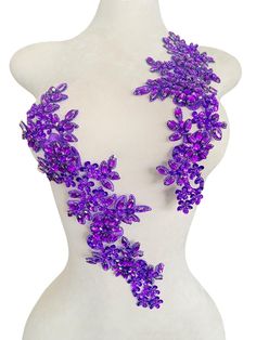 a white mannequin with purple flowers on it's neck and two rows of beads