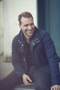 a man sitting on top of a bench smiling