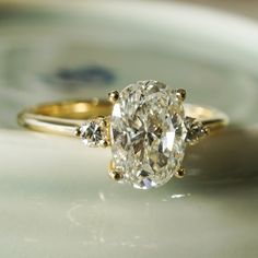 an oval diamond ring with three small diamonds on the band, set in yellow gold