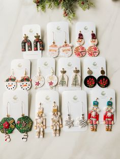 many pairs of earrings are laid out on the table next to each other, including santa and snowmen