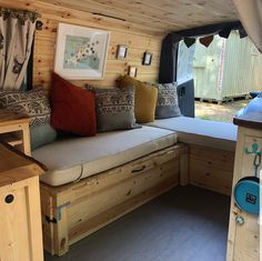 the inside of a small wooden cabin with lots of pillows on it's bed