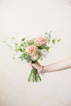 a person holding a bouquet of flowers in their hand with the other hand on it