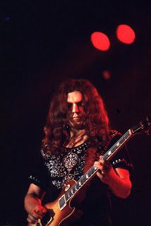 a man with long hair playing an electric guitar