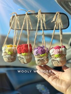 three small crocheted ice cream cones are hanging from a car's dashboard