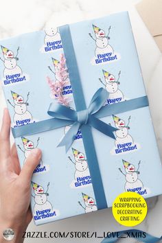 a person holding a wrapped gift box with snowmen on it