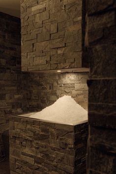 a large pile of white snow sitting on top of a stone wall next to a fire place