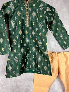 Boys Kurta Pajama Set in Raw Silk material with Cotton Lining. Kurta has Ikkat designs on the back, front and sleeves. The neckline has beautiful lace work and fancy buttons. Item : Boys Kurta PajamaReady to Wear : YesKurta Color : Bottle Green Kurta Fabric : Raw Silk (Non-Pure)Pajama Color : Gold Fabric : Raw Silk (Non-Pure)Pocket : YesLining (Yes/No) : Yes (Cotton Lining in Kurta)Disclaimer- There can be little variation in the color due to screen resolution setting, phone display setting or a Kurta Pajama For Boys, Indian Boy, Phone Display, Boys Kurta, Fancy Buttons, Kurta Pajama, Boys Wear, Gold Fabric, Boys Pajamas