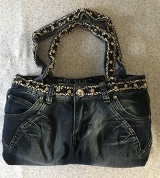 This jean purse is beautifully garnished with silver brades and eye catching glass button. The band and handle straps are covered with dark blue raveled trim with large silver and glass brades. The back pockets are garnished with rows of five star glass gems. The purse is fully lined with western blue handkerchief fabric with two inside pockets. The purse has a Velcro fascine. the size of the purse is 16 inches wide and 9 inches tall. Jean Bag Aesthetic, How To Make A Purse Out Of Jeans, Jean Pocket Purse, Purse Aesthetic, Jean Bag, Blue Handkerchief, Jean Purses, Denim Crafts Diy, Fashion Jobs