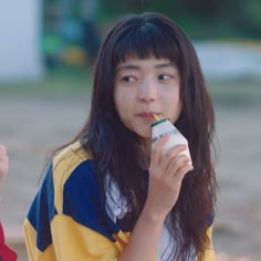 a young woman holding a drink in her hand