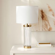 a white table with a lamp and some books on it