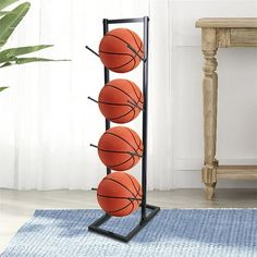 three basketballs are hanging on a rack in front of a table with a potted plant