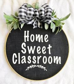 a black and white sign with the words home sweet classroom written on it, surrounded by greenery