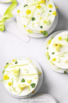 three cakes decorated with yellow flowers and green leaves on white plates next to utensils