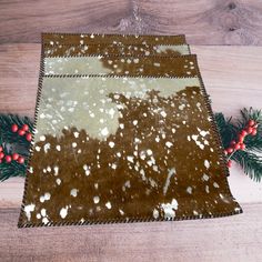 a brown and white rug on top of a wooden floor next to pine branches with red berries