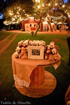 a wooden table topped with lots of small boxes and candles on top of a lush green field