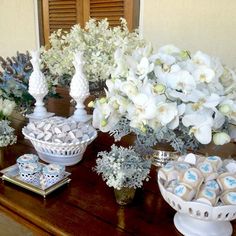 a table topped with vases filled with white flowers and cookies on top of it