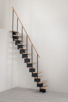 an empty room with a stair case and wooden handrail in the center, against a white wall