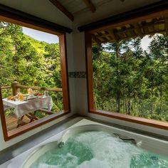 a large jacuzzi tub sitting inside of a bathroom next to two windows overlooking trees